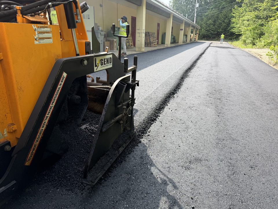 Asphalt being placed with a paver on a private road