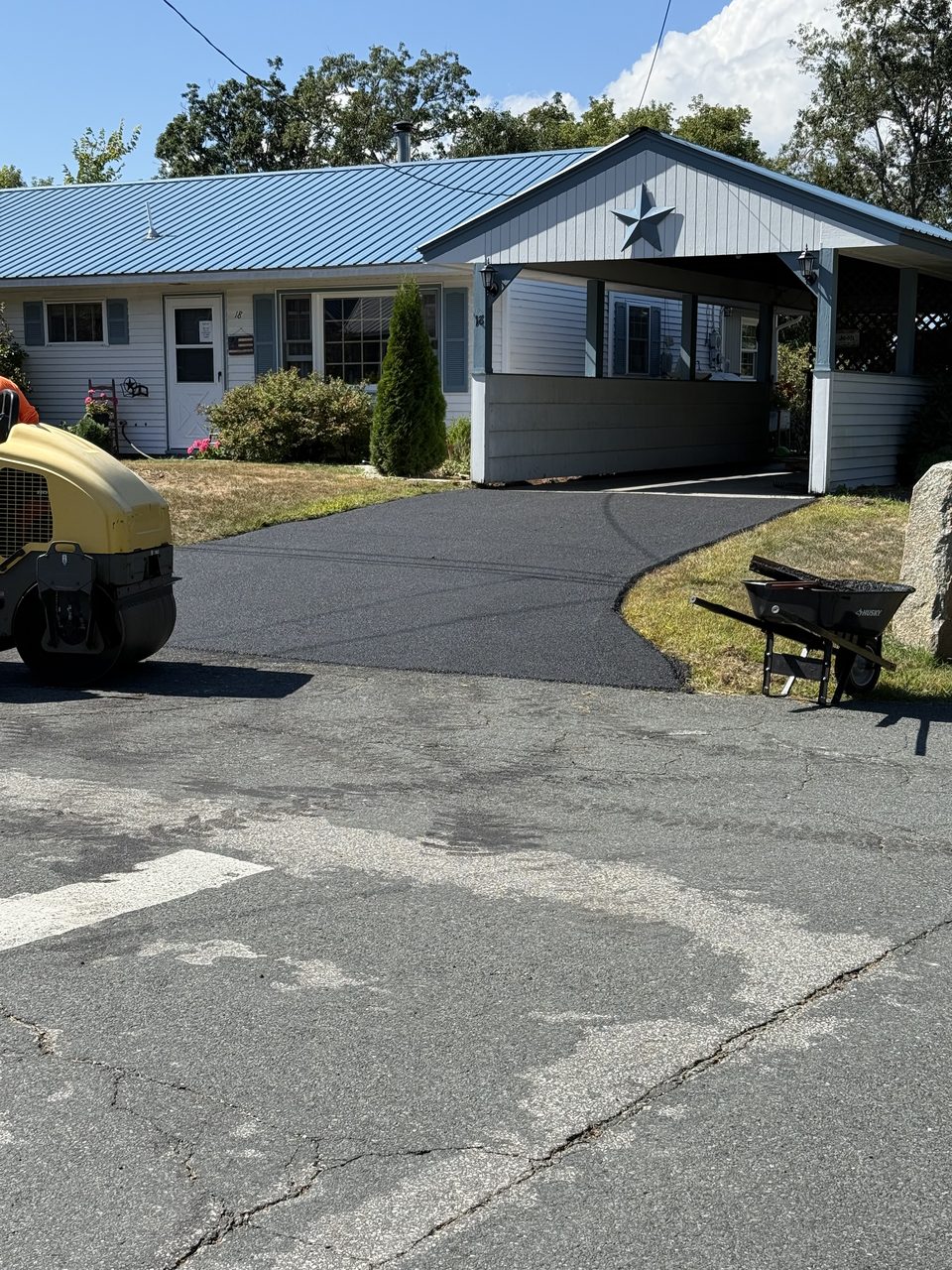 Curved asphalt driveway leading to a carport